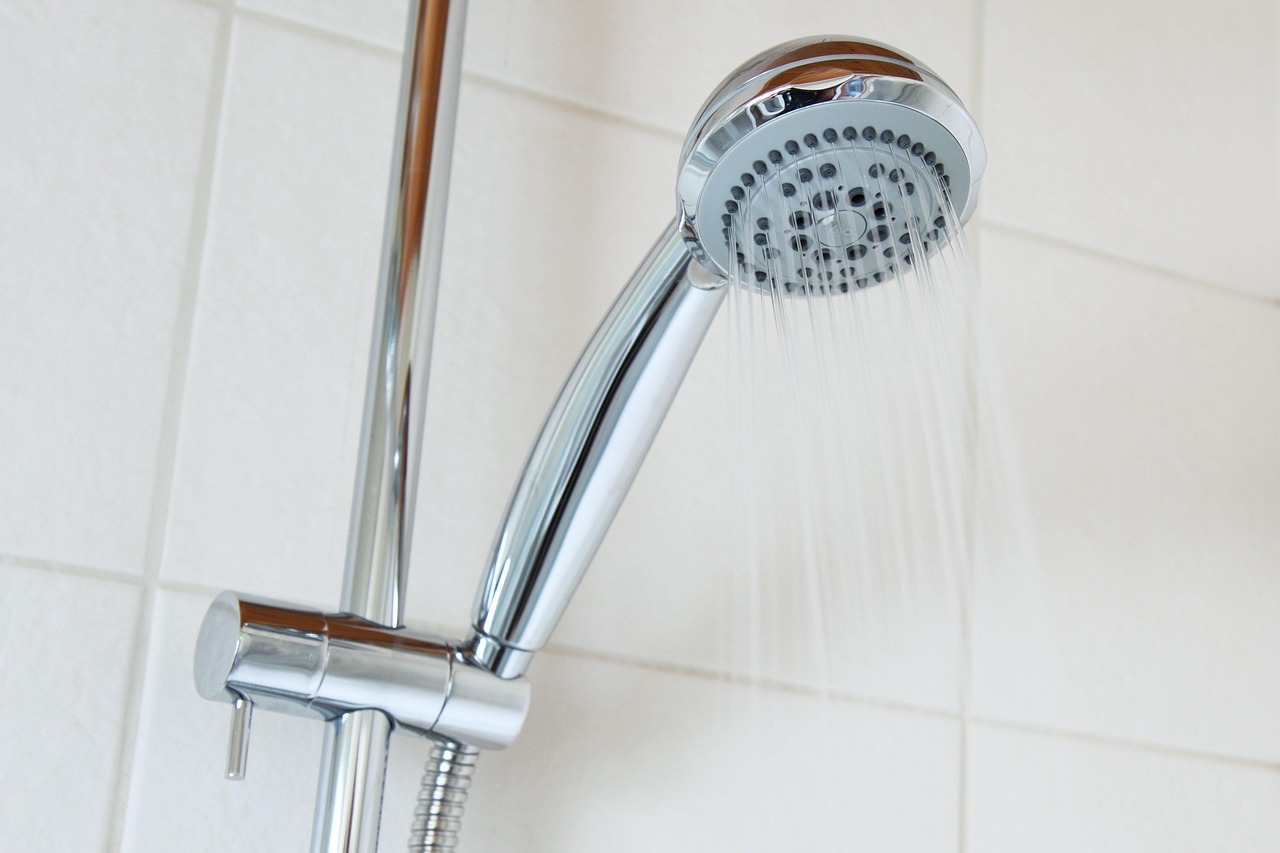 Matte black shower valve and head on beige tile